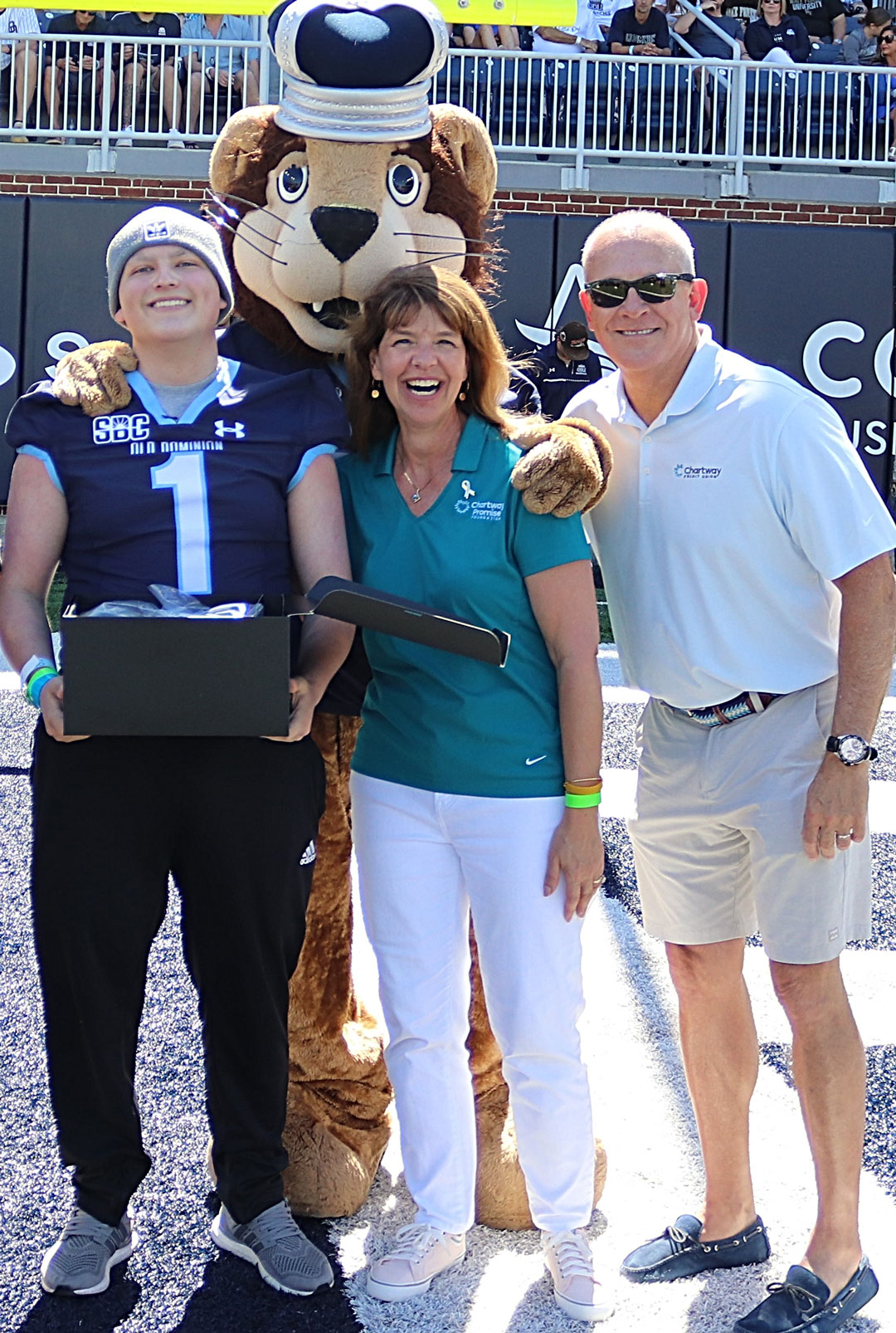 Pictured from left: “Levi” (wish recipient); “Big Blue” Old Dominion University mascot; Christine Wilson, president, Chartway Promise Foundation; Brian T. Schools, president/CEO, Chartway Credit Union. Thanks to the Chartway Promise Foundation and Toby’s Dream Foundation, Levi, a 17-year-old amputee and battling Synovial sarcoma, can now relive the experience of running using Virtual Reality goggles and omnidirectional treadmill.